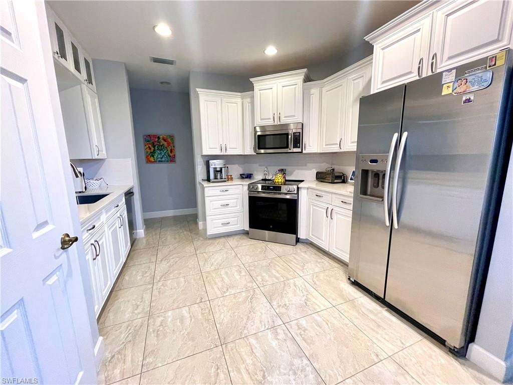 Kitchen featuring stainless steel appliances, white cabinetry, recessed lighting, and glass insert cabinets