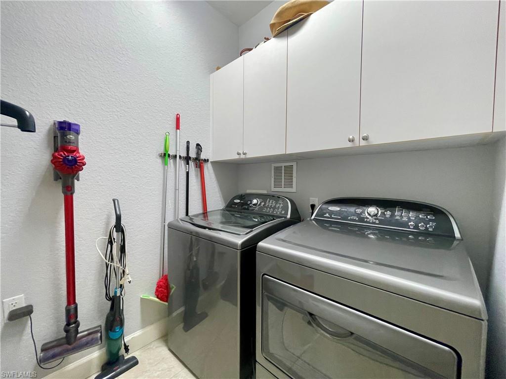 Laundry room featuring a textured wall, cabinet space, and separate washer and dryer