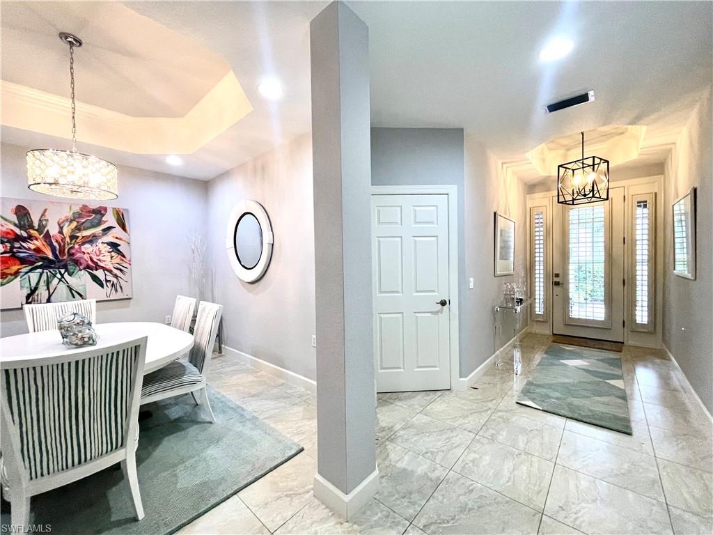 Entrance foyer featuring a chandelier, a tray ceiling, light marble finish flooring, and recessed lighting