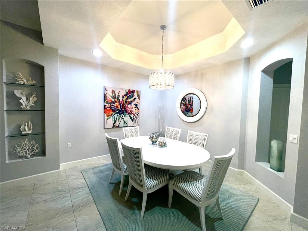 Dining room featuring a chandelier, a raised ceiling, and built in features
