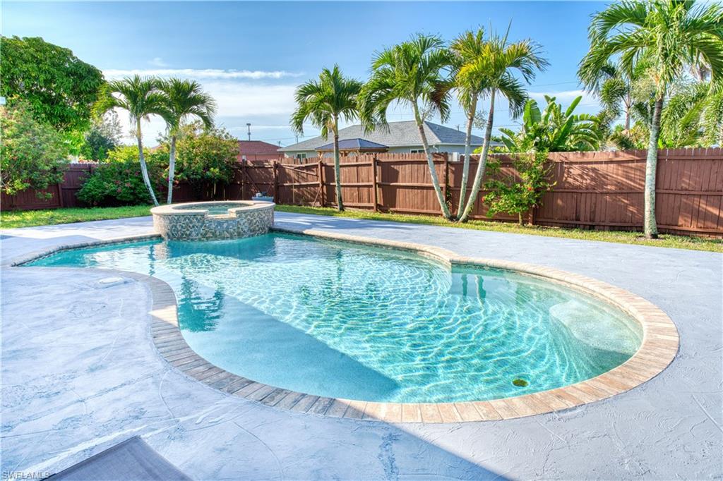 View of swimming pool with a fenced backyard, a pool with connected hot tub, and a patio