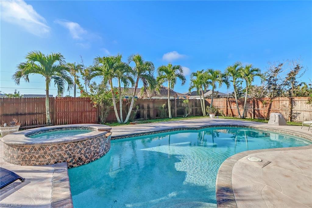 Rear view of property featuring a patio area, stucco siding, a pool with connected hot tub, a metal roof, and a standing seam roof