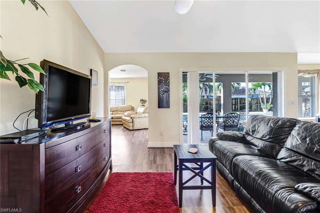 Living room with vaulted ceiling, ceiling fan, wood finished floors, and arched walkways