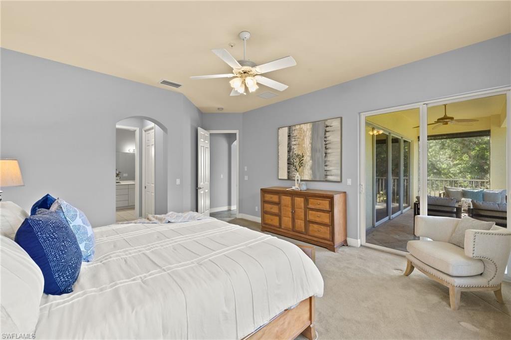 Bedroom with carpet floors, visible vents, baseboards, arched walkways, and access to outside