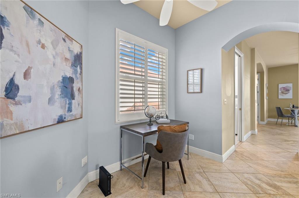 Home office featuring arched walkways, a ceiling fan, and baseboards