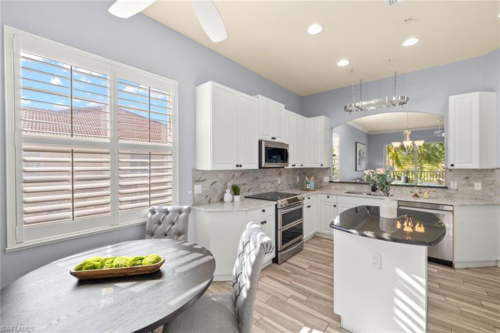 Kitchen with a center island, stainless steel appliances, white cabinets, backsplash, and recessed lighting
