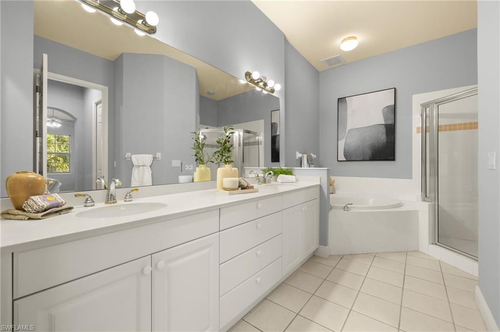 Bathroom featuring a sink, a stall shower, tile patterned flooring, double vanity, and a garden tub