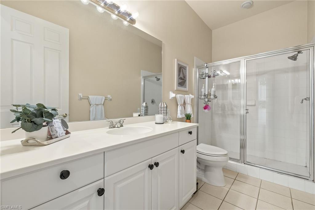 Bathroom featuring vanity, toilet, a shower stall, and tile patterned floors