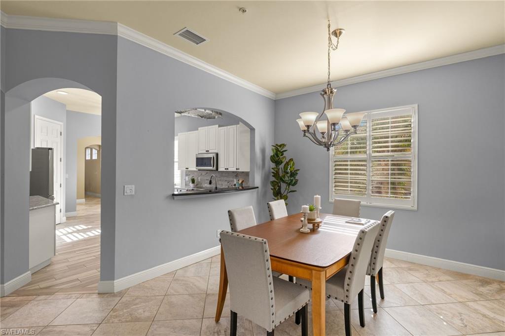Dining area featuring ornamental molding, visible vents, a chandelier, arched walkways, and baseboards