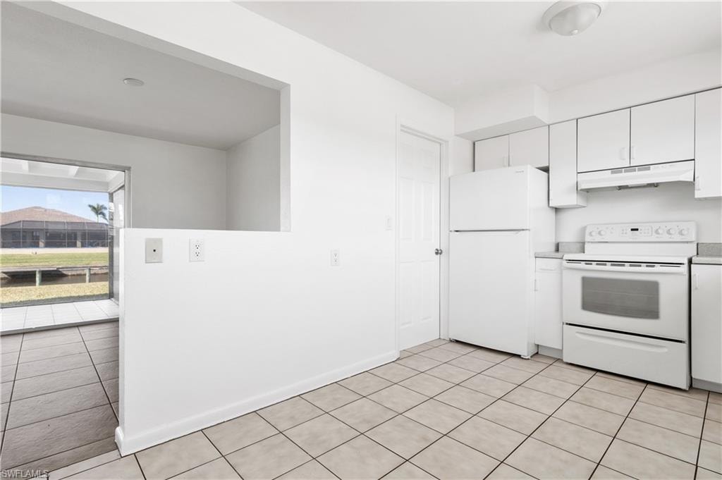 Kitchen with white cabinetry, light tile patterned floors, and white appliances