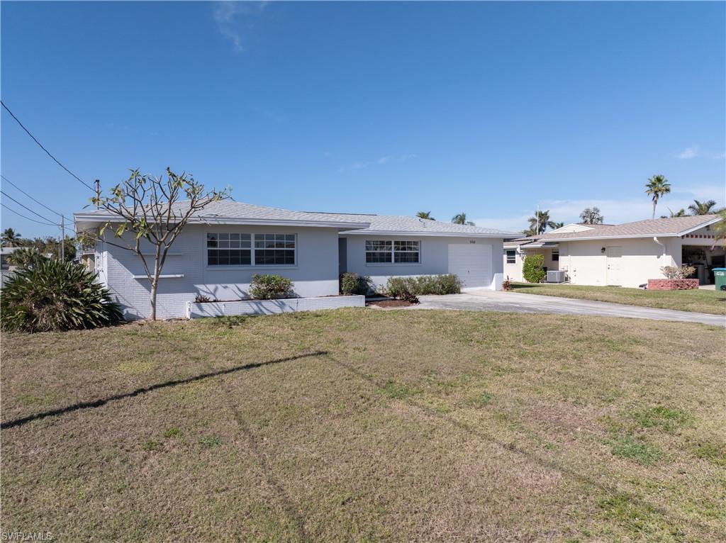 Ranch-style house with cooling unit, a garage, and a front lawn