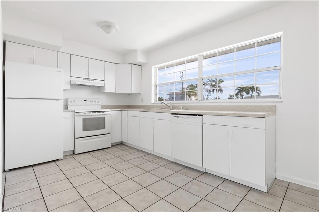 Kitchen with sink, a wealth of natural light, white cabinets, and white appliances