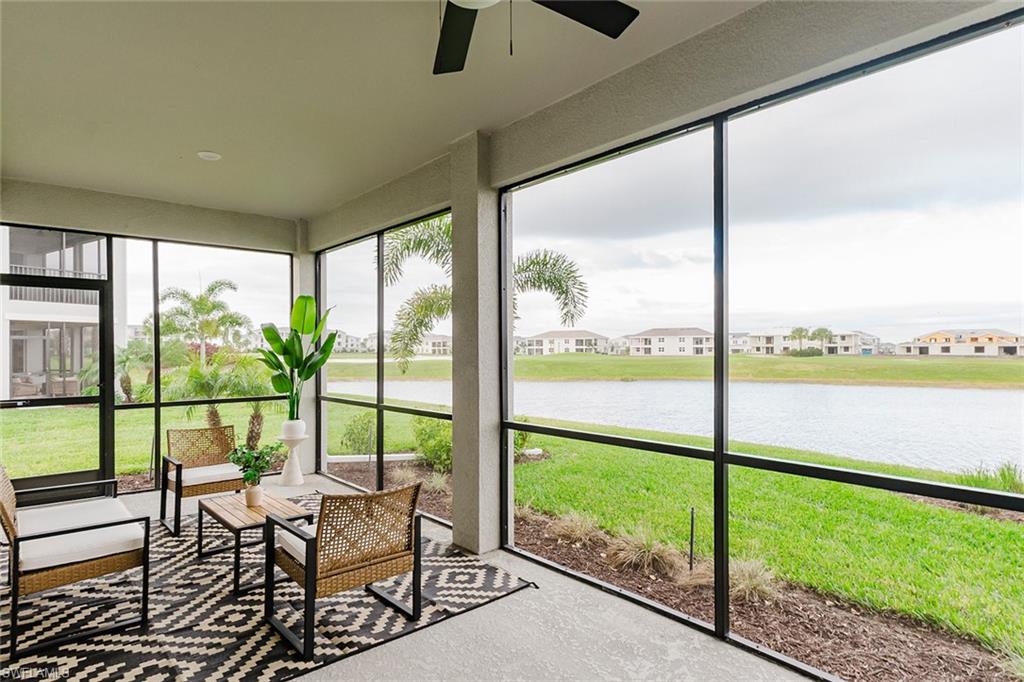 Sunroom featuring a residential view, a water view, and a ceiling fan