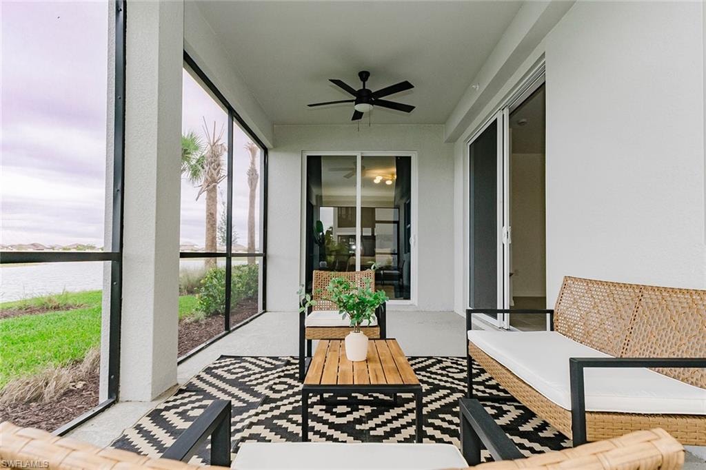 Sunroom / solarium featuring a ceiling fan and a water view