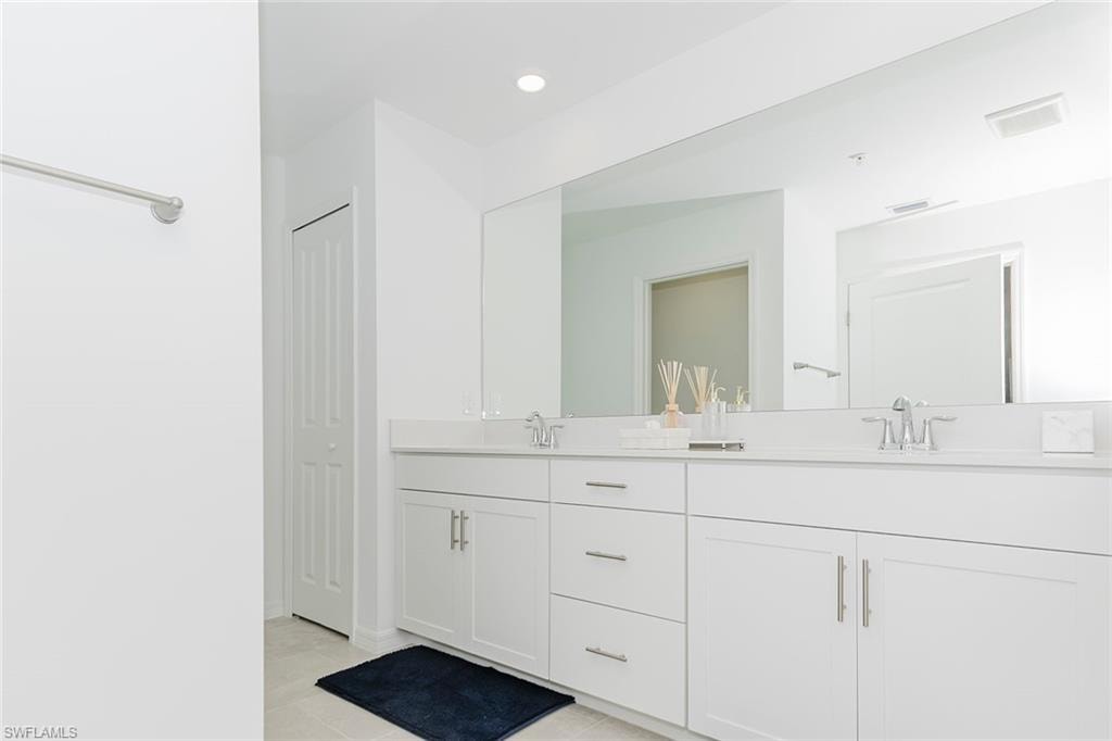 Full bathroom with double vanity, a closet, light tile patterned floors, and recessed lighting