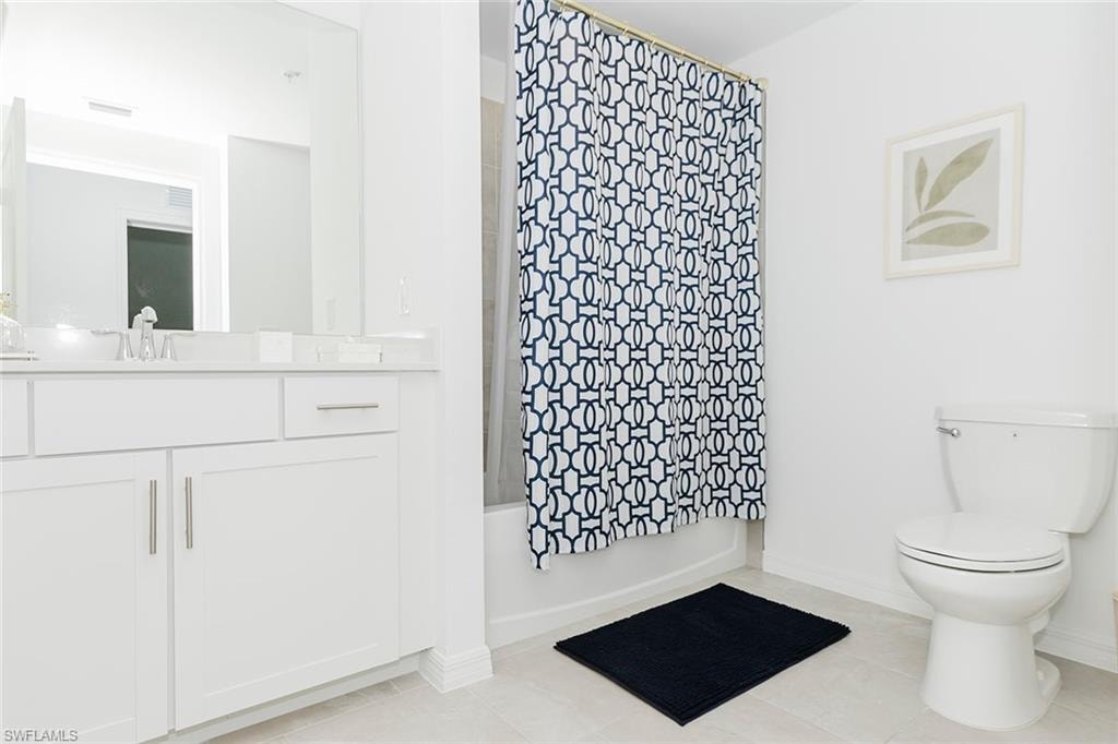 Full bath featuring vanity, shower / bath combination with curtain, and light tile patterned flooring
