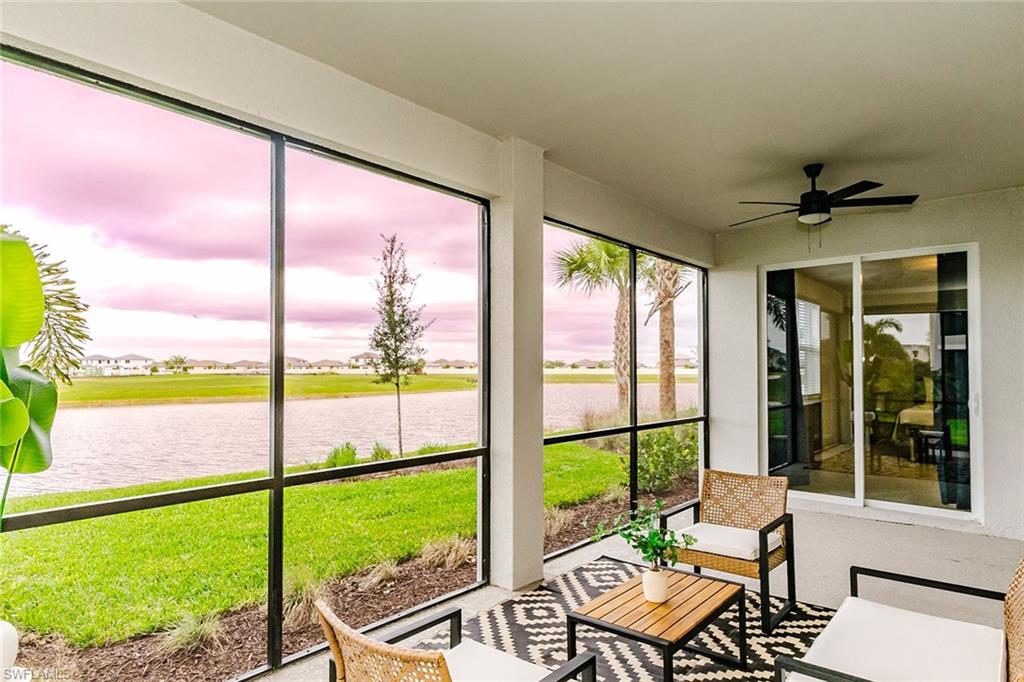 Sunroom / solarium with a ceiling fan, a water view, and a residential view