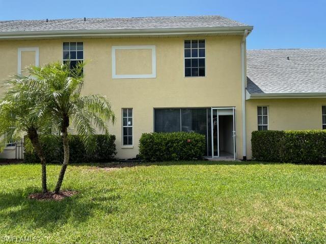 Back of house featuring stucco siding and a yard