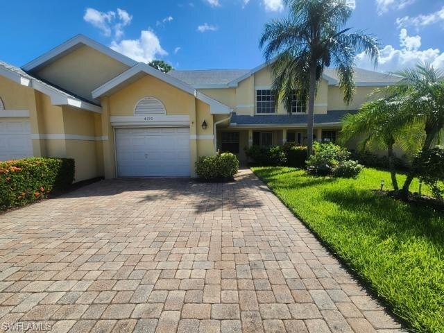 View of front facade with stucco siding, decorative driveway, and an attached garage