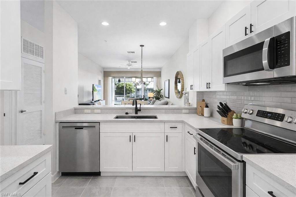 Virtual staged kitchen featuring stainless steel appliances, white cabinetry, light stone counters, and tasteful backsplash