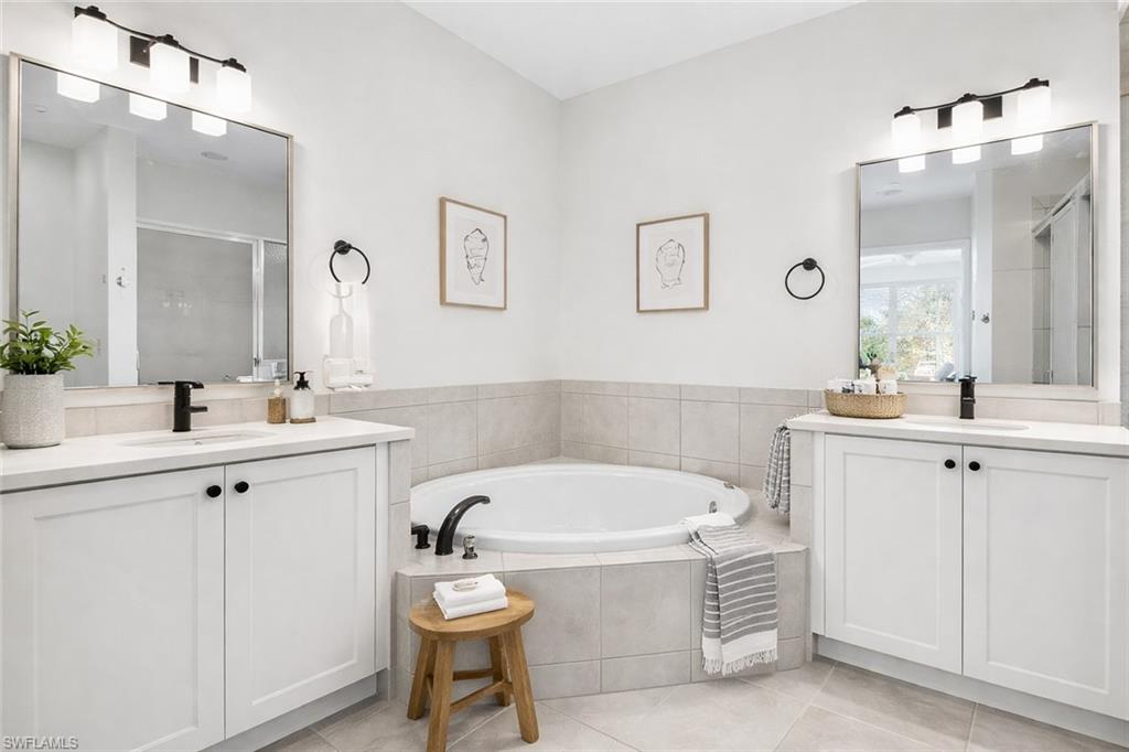 Virtual staged full bathroom featuring two vanities, a shower stall, a bath, and light tile patterned flooring