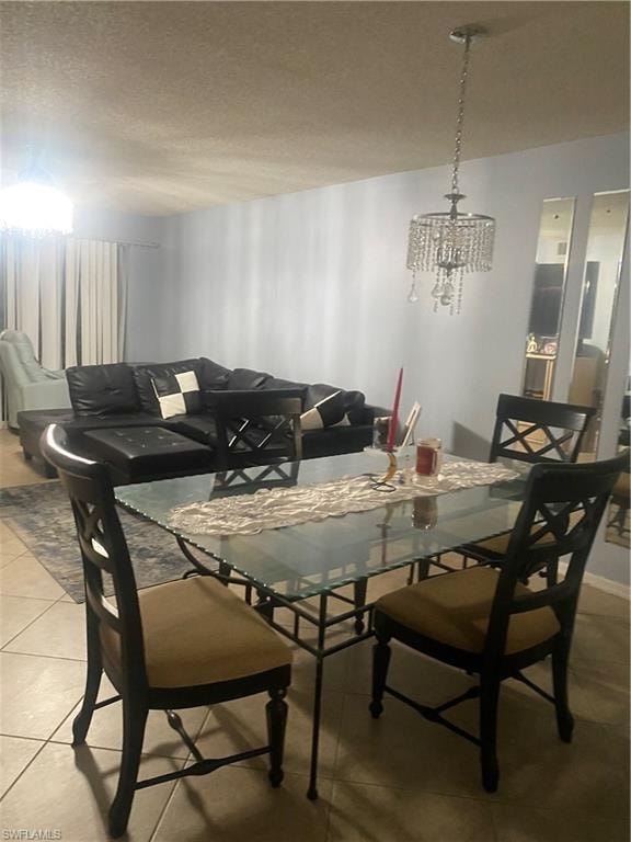 Tiled dining room featuring a chandelier and a textured ceiling