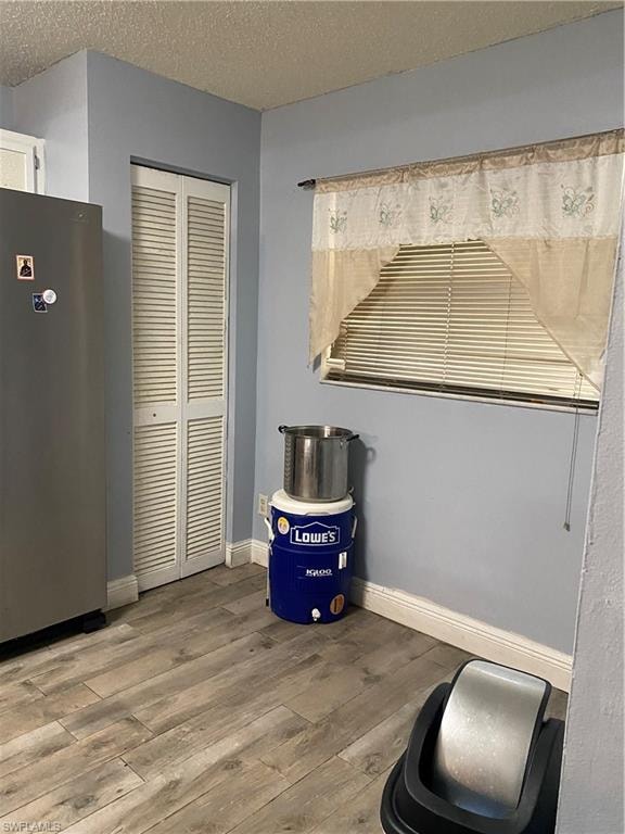 Detailed view of fridge, wood finished floors, and a textured ceiling