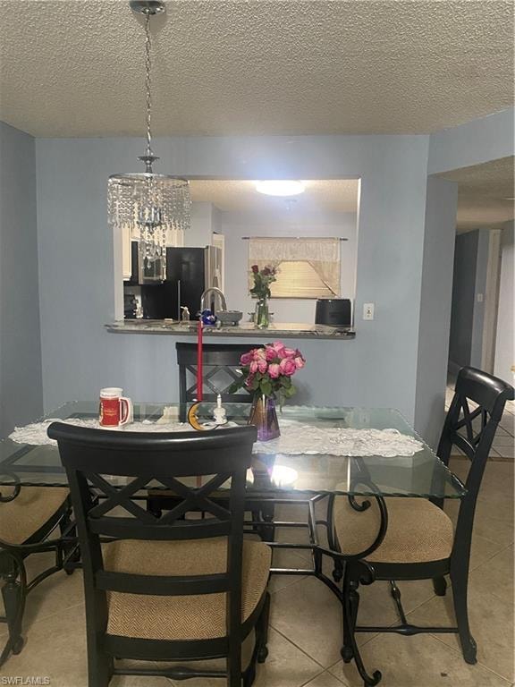 Tiled dining space featuring a textured ceiling and a chandelier