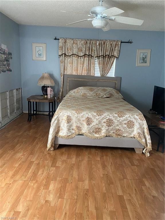 Bedroom with light wood finished floors, a textured ceiling, and ceiling fan