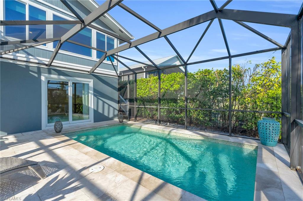 Swimming pool featuring a sunroom, glass enclosure, and a patio