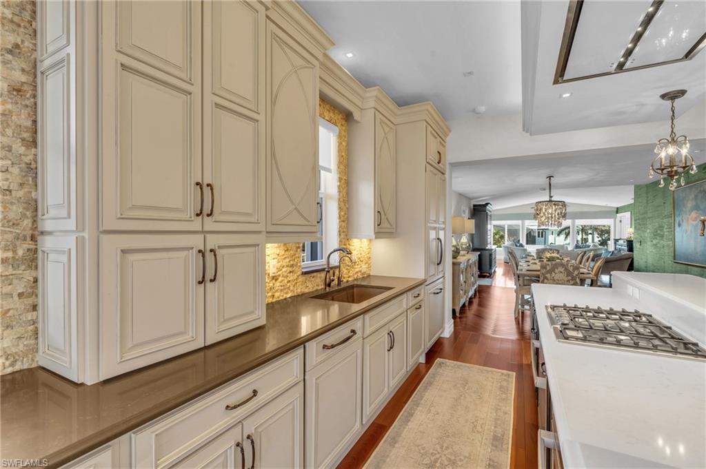 Kitchen featuring decorative light fixtures, dark wood-style floors, open floor plan, vaulted ceiling, and cream cabinetry