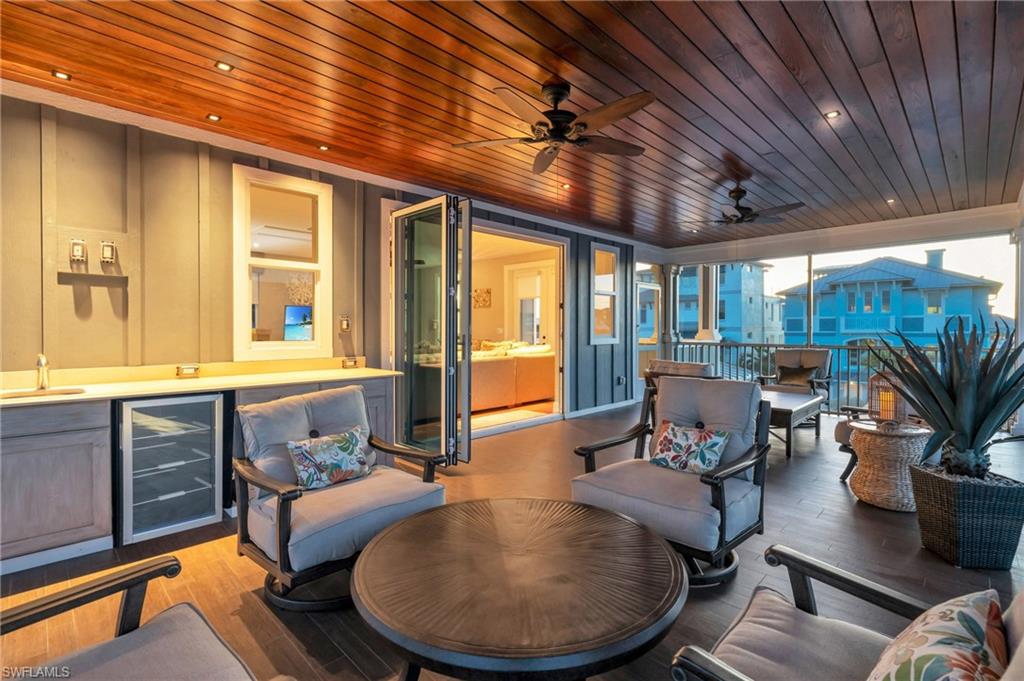 View of patio with wine cooler, ceiling fan, outdoor dining area, and outdoor lounge area
