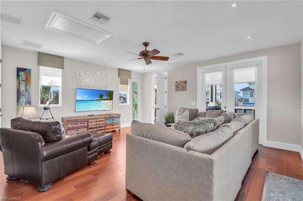 Living room with wood finished floors, a ceiling fan, and french doors