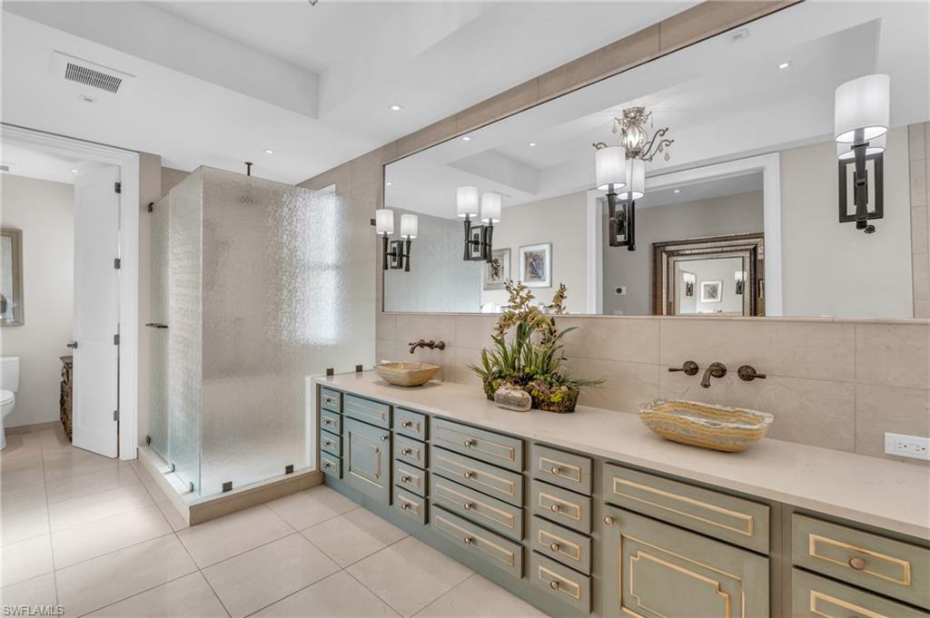 Bathroom featuring a shower stall, backsplash, double vanity, light tile patterned floors, and recessed lighting