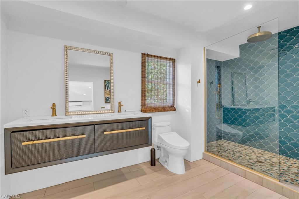 Full bathroom featuring a stall shower, double vanity, light wood-type flooring, and recessed lighting