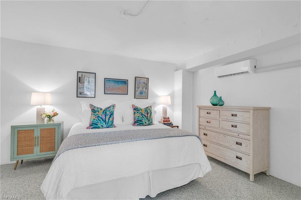 Bedroom with light colored carpet and an AC wall unit