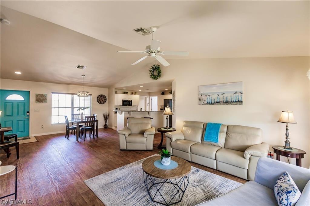 Living room featuring lofted ceiling, wood finished floors, and a ceiling fan