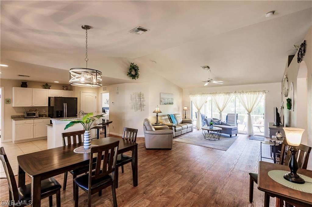 Dining area with vaulted ceiling, light wood finished floors, a ceiling fan, and recessed lighting