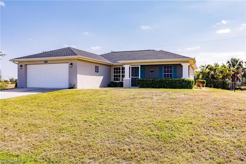 Ranch-style house with stucco siding, a front lawn, a garage, and driveway