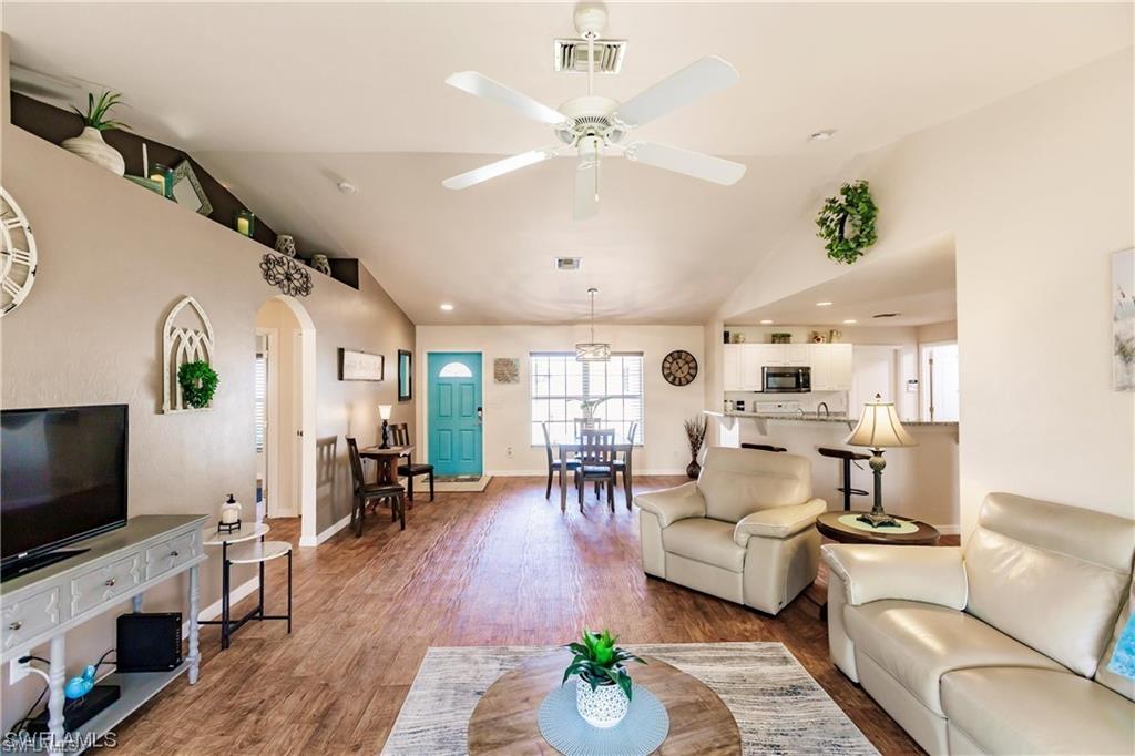 Living area with lofted ceiling, wood finished floors, arched walkways, ceiling fan, and recessed lighting