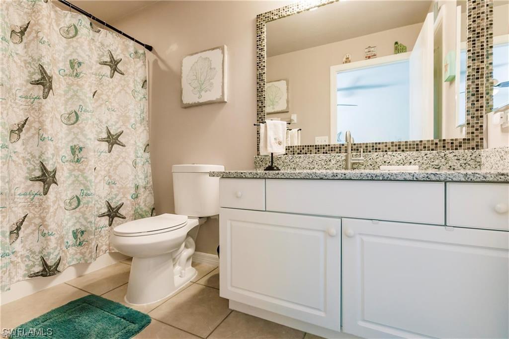 Full bathroom with light tile patterned floors, vanity, and a shower with shower curtain