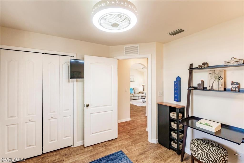 Bedroom featuring arched walkways, light wood-style floors, and a closet