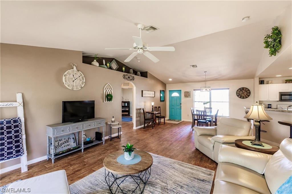 Living area with wood finished floors, arched walkways, lofted ceiling, and a ceiling fan