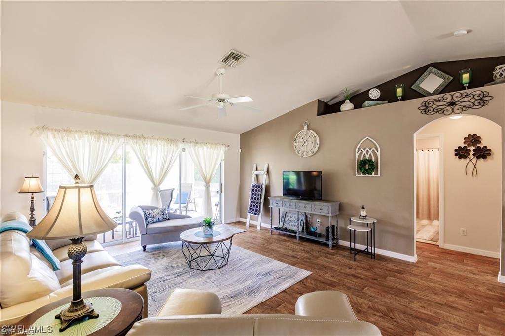 Living room featuring lofted ceiling, arched walkways, wood finished floors, and ceiling fan