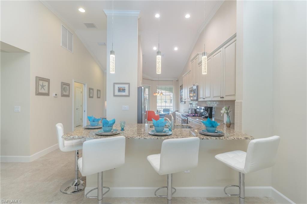 Kitchen featuring a breakfast bar, crown molding, tasteful backsplash, a peninsula, and light stone counters