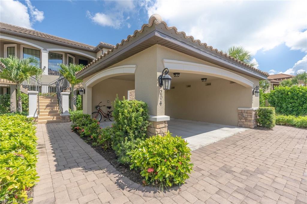 View of front of house with stucco siding, a tiled roof, stairway, and stone siding