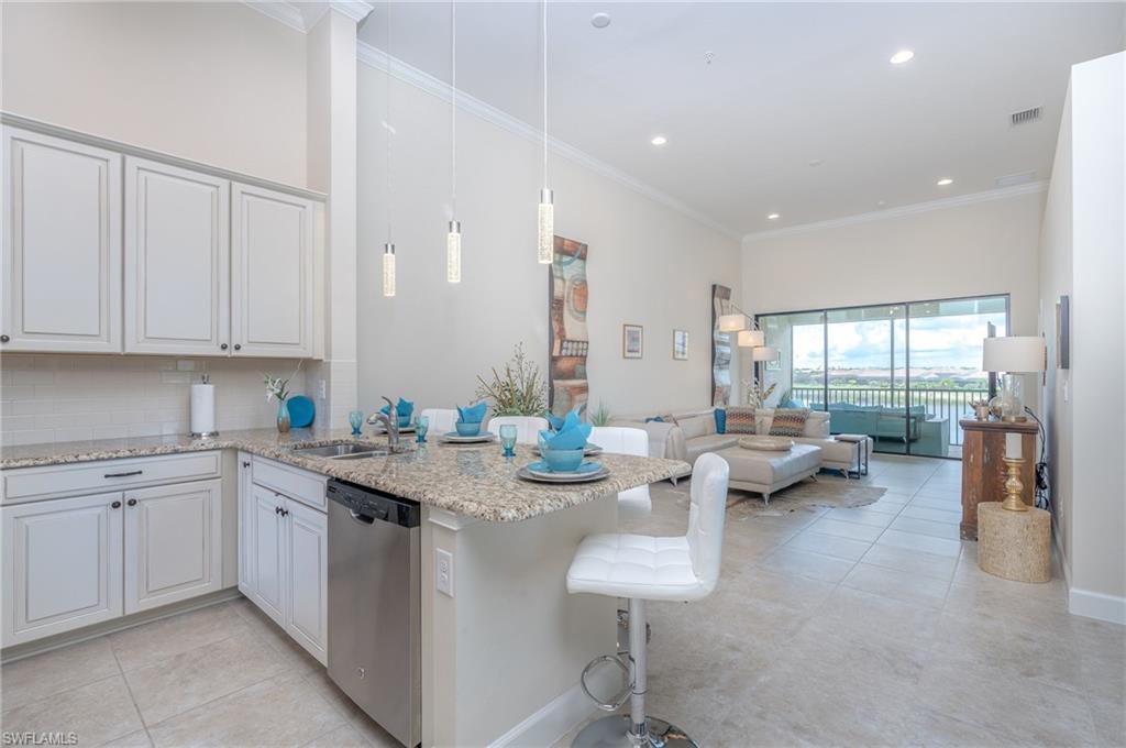 Kitchen featuring crown molding, decorative backsplash, light stone countertops, stainless steel dishwasher, and pendant lighting