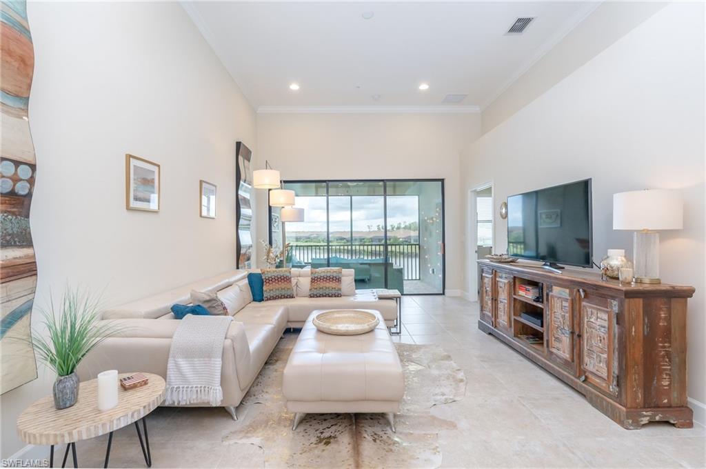 Tiled living area with crown molding, recessed lighting, and a towering ceiling