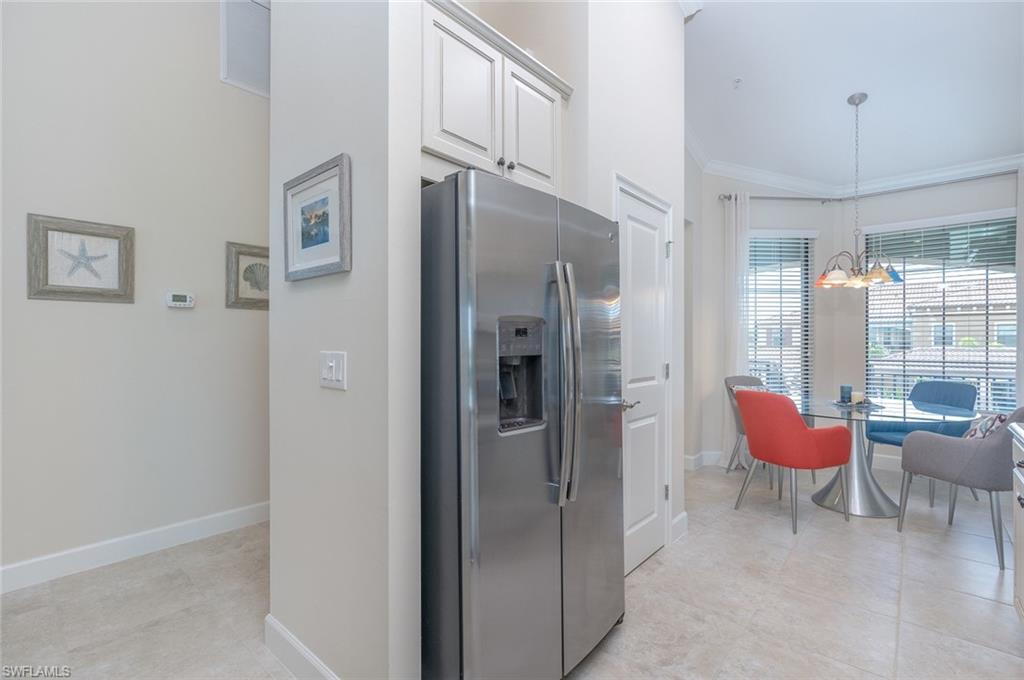 Kitchen with stainless steel refrigerator with ice dispenser, decorative light fixtures, white cabinetry, a chandelier, and crown molding