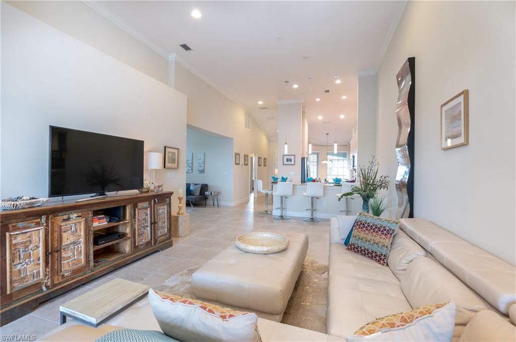 Living room with ornamental molding, recessed lighting, light tile patterned floors, and a towering ceiling